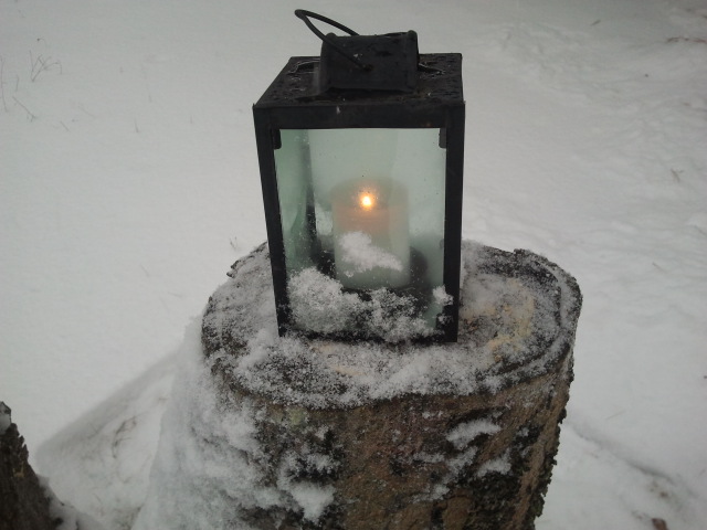 En liten låga flämtar inne i den av snö och is prydda lyktan.