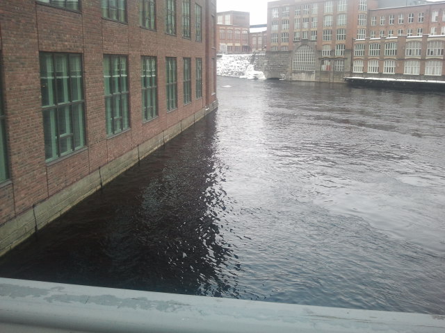 Fabriksområde omgivet av vatten och forsar. Ser nästan lite läbbigt ut med vatten alldeles fast i väggen.