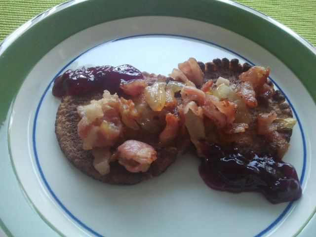 Plättar toppade med en blandning av stekt bacon och lök samt lingonsylt.
