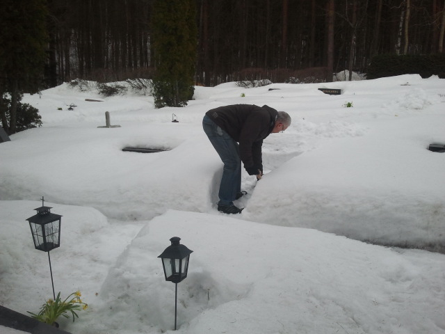 Maken röjer snö från sin farmors och farfars grav.