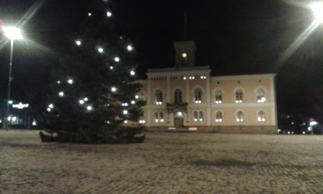 I väntan på bussen. En kur finns på torget. Det här är vårt rådhus och stadens julgran.