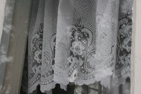 En vacker spetsgardin i fönstret till lilla verandan.