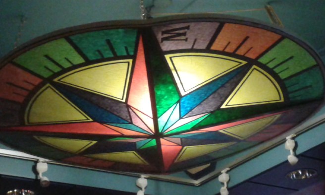 I hotellets bar finns en kompass i taket. Kanske tänkt som vägvisare åt folk, så de hittar hem efter krogkvällen. Vi stannade bara två timmar, för jag ville se en del av OS-invigningen på tv.