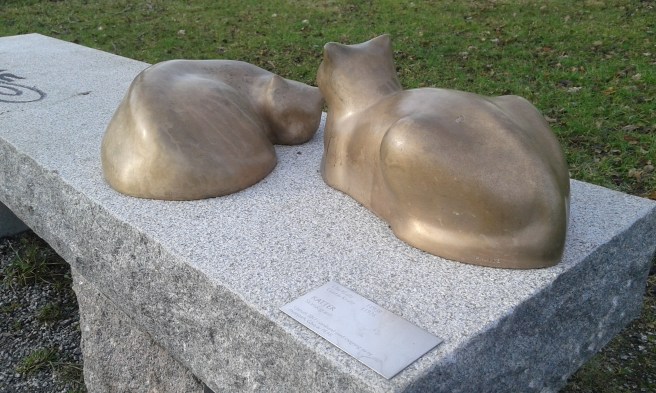 Katter vilar på en bänk. Konst i en park invid Eskilstuna å.