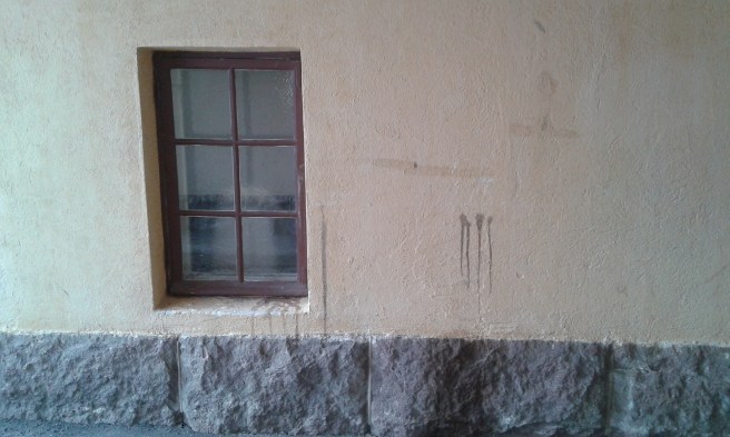 Fönster, vägg och stenfot i samma portgång.