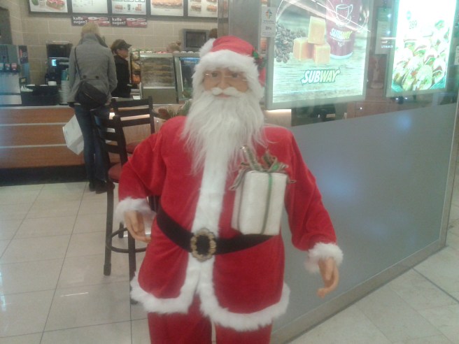 En rockande tomte utanför en affär.