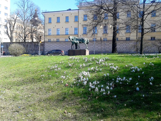 Vackra vårblommor och statyn Moderskärlek.