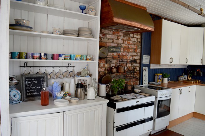 Ett stort, ljust och på alla sätt inbjudande kök med vacker tegelvägg.