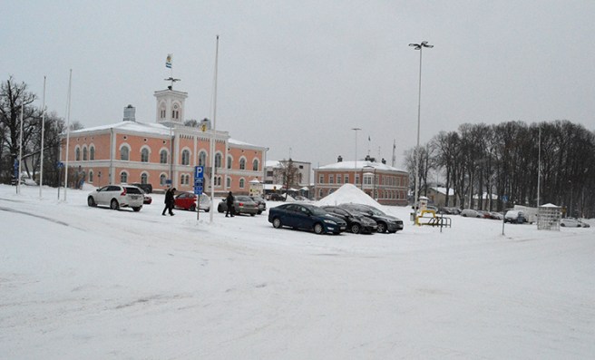 Torget. Några personer hastar framåt hukande i snöyran.